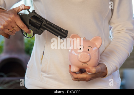 Cina rosa salvadanaio minacciato con una pistola Foto Stock