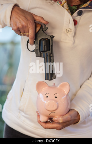 Cina rosa salvadanaio minacciato con una pistola Foto Stock