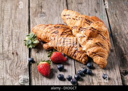 Due croissant fresco con frutti di bosco su un vecchio tavolo di legno. Foto Stock