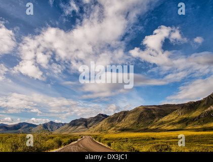 Strada sterrata in Yukon Territory in estate con il cielo blu e nuvole. Foto Stock