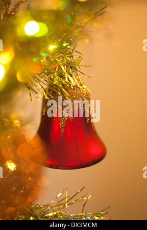 Red bell ornamento appesa illuminato albero di Natale, close up Foto Stock