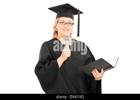 Donna matura in abito di graduazione di lettura su un microfono Foto Stock