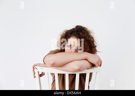 Triste giovane donna seduta su una sedia Foto Stock