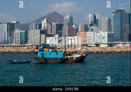 Il alti edifici di Kwun Tong forniscono lo sfondo di questo cinese la pesca in barca nel porto Victoria, Hong Kong S.A.R Foto Stock