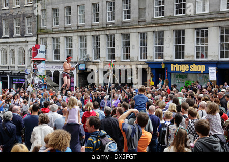 Street Performer Kwabana Lindsay su una corda lenta che intrattiene una folla di persone durante l'Edinburgh Festival Fringe, Scozia, Regno Unito Foto Stock