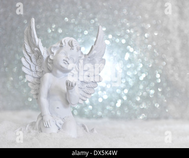 Poco bianco angelo custode in neve sulle luci brillanti sfondo. Decorazione di natale Foto Stock