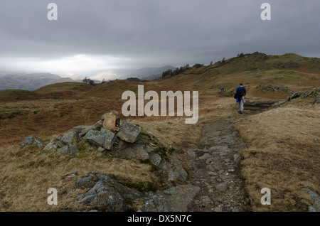 Un uomo solitario a piedi verso il vertice di nero cadde, Lake District, Inghilterra in una fredda giornata grigia. Foto Stock