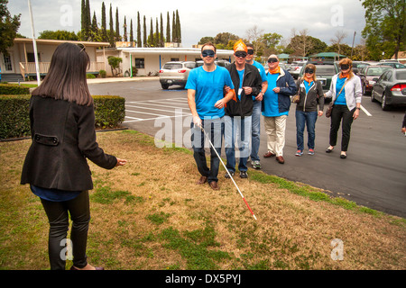 I visitatori di una scuola per ciechi di Tustin, CA, sono gli occhi bendati per consentire loro di fare esperienza sightlessness come imparano ad usare un bastone bianco per camminare in un parcheggio. Foto Stock