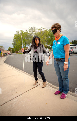 I visitatori di una scuola per ciechi di Tustin, CA, sono gli occhi bendati per consentire loro di fare esperienza sightlessness come imparano ad usare un bastone bianco per camminare in un parcheggio. Foto Stock