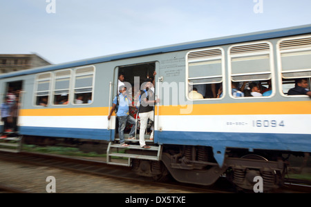 Persone appesi da aprire le porte del treno dei pendolari passando attraverso il Mount Lavinia stazione ferroviaria di Colombo Foto Stock