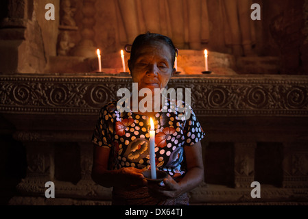 Il vecchio donna asiatica pregando nel tempio antico con la luce di una candela Foto Stock