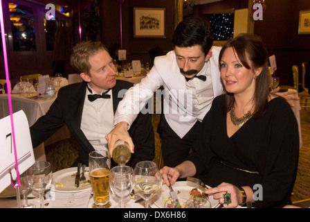 Attore omaggio giocando sfortunato cameriere manuel dalla BBC TV Fawlty Towers serve diners Foto Stock