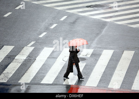 Persone che trasportano gli ombrelli sotto la pioggia a piedi attraverso il passaggio pedonale in Shibuya, Tokyo, Giappone Foto Stock