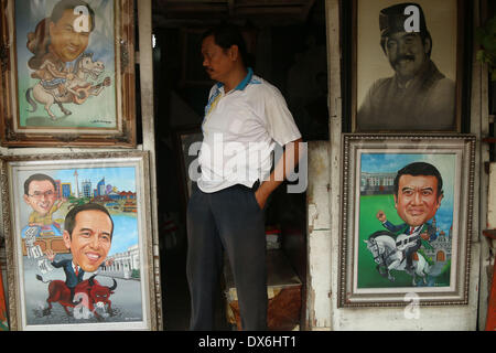 Jakarta, DKI Jakarta, Indonesia. Xix Mar, 2014. Un artista pittore sorge vicino al display di una pittura di Giacarta governatore Joko Widodo( seguente a sinistra), e un musicista Dangdut, Rhoma Irama (in basso a destra) a Street Painting Shop venditore in Jakarta. Marzo 19, 2014 . Joko Widodo chi è in esecuzione per il presidente per il Partito Democratico Indonesiano di Lotta (PDI-P) e Rhoma Irama un presidente candidato per il risveglio nazionale partito (CPC). Foto Stock