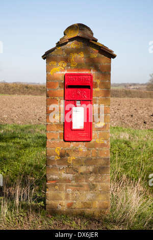 Rosso scarlatto Post Office casella montante montato in laterizio con campi in background, Hoo, Suffolk, Inghilterra Foto Stock