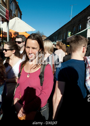 Piuttosto giovane donna in maglia rosa a piedi nella affollata Columbia Road Flower Market East End di Londra E2 Inghilterra UK KATHY DEWITT Foto Stock