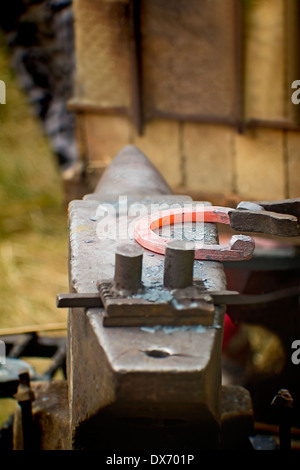 In una piccola fucina fucina di un ferro di cavallo a caldo. Il lavoro manuale. Foto Stock