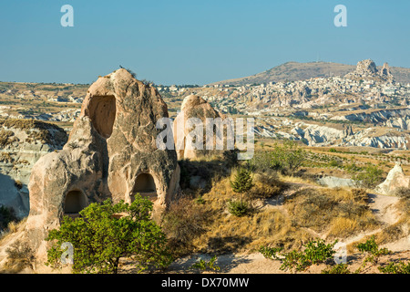 Abitazioni di Camini di Fata e Uchisar (R) in distanza, Red Valley, Cappadocia, Turchia Foto Stock