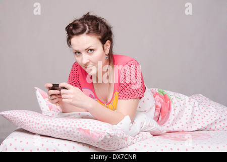 La ragazza che giace nel letto e parlando al telefono Foto Stock