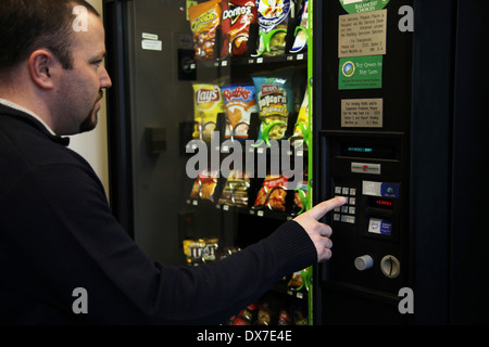 Uomo di acquistare un junk food snack da un distributore automatico, New York, Stati Uniti d'America Foto Stock