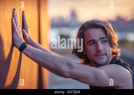 Un giovane uomo avente un predeterminato tratto di allenamento prima di un inizio di mattina allenamento Foto Stock