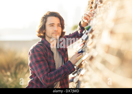 Un giovane uomo che guarda pensieroso e grave in una impostazione all'aperto Foto Stock