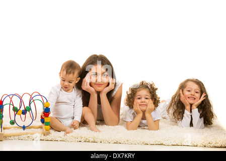 Bella famiglia posa in una fila sul tappeto di pelliccia home contro uno sfondo bianco Foto Stock