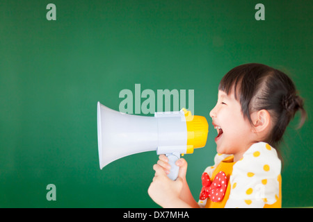 Capretto felice grida qualcosa in un megafono con scheda Foto Stock