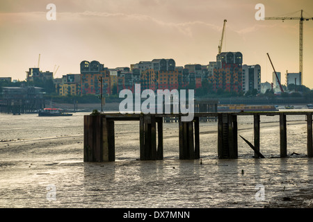 Tide fuori sul Fiume Tamigi rivelando fango banche; guardando verso moderni appartamenti residenziali e appartamenti a Greenwich, Londra Foto Stock