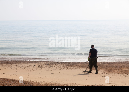 Un uomo con rilevatore di metalli nelle acque a bordo di mare spiaggia. Foto Stock