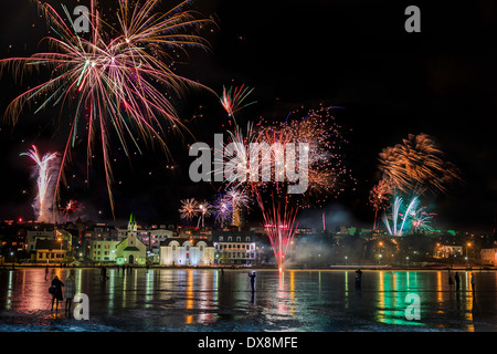 Fuochi d'artificio a Capodanno oltre lo stagno a Reykjavik, Islanda Foto Stock