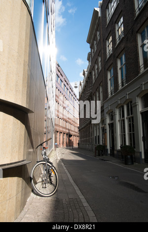 Bicicletta appoggiata contro un edificio moderno nel centro di Amsterdam Paesi Bassi Foto Stock