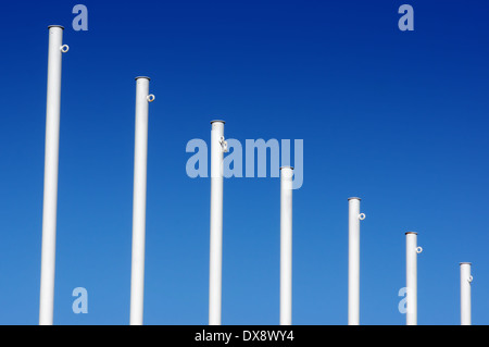 Vuoto bandiera bianca poli contro il cielo blu Foto Stock