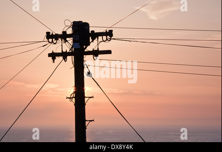 Fotografia del palo del telegrafo e i fili in silhouette sullo sfondo di un estate tramonto sul mare irlandese di Tresaith Cardigan Foto Stock