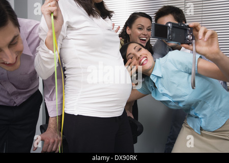 Ufficio i colleghi fotografare in parte con la collega in stato di gravidanza Foto Stock