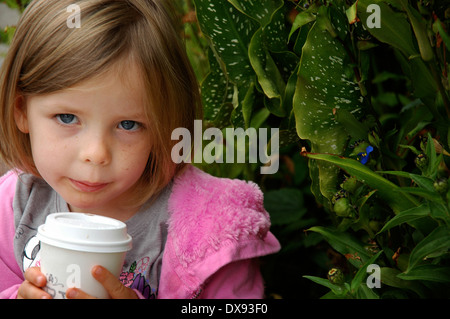 Una giovane ragazza bionda raffredda la sua bevanda calda la mattina presto fuori dal Verve Coffee a Santa Cruz, California. Foto Stock