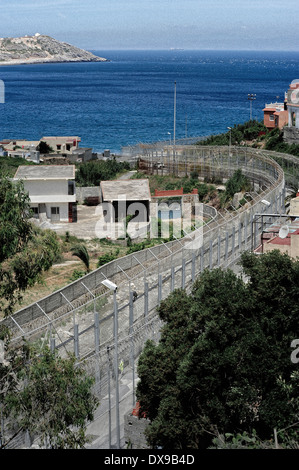 Recinzioni perimetrali in villaggio Benzu che separa le enclave spagnole di Ceuta e Marocco, lo stretto di Gibilterra in background. Foto Stock