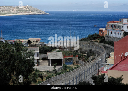 Recinzioni perimetrali in villaggio Benzu che separa le enclave spagnole di Ceuta e Marocco, lo stretto di Gibilterra in background. Foto Stock