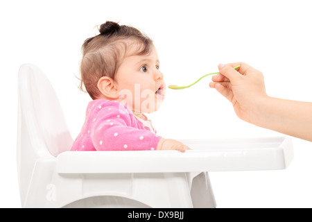 Baby girl essendo alimentato in una sedia di alimentazione Foto Stock