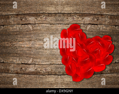 Cuore rosso a forma di petali di rosa su legno rustico sfondo. Il giorno di San Valentino sfondo Foto Stock
