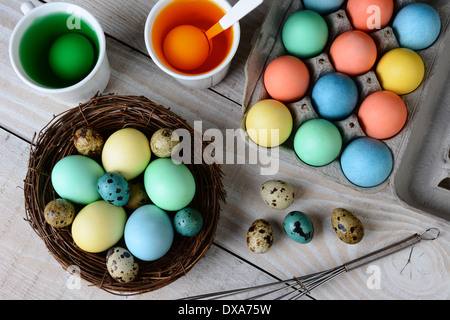 Angolo di alta vista di uovo di pasqua di morire. Tinti le uova in un nido con uova in soluzione di colorante e altre uova pronti per essere inzuppati. Foto Stock