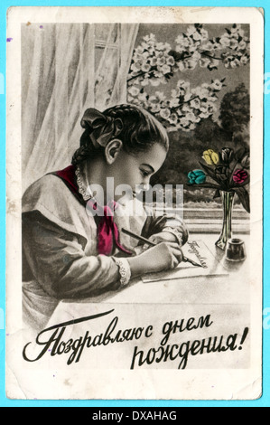 Unione Sovietica - circa 1960: cartolina stampato in URSS mostra Schoolgirl scrive saluto, circa nel 1960. Testo in russo: Buon compleanno! Foto Stock