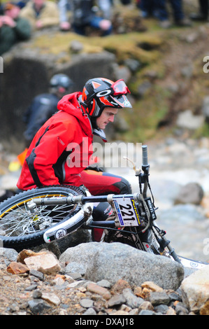 Un uomo seduto accanto a un percorsi bike accanto a un fiume, durante il SSDT prove. Foto Stock