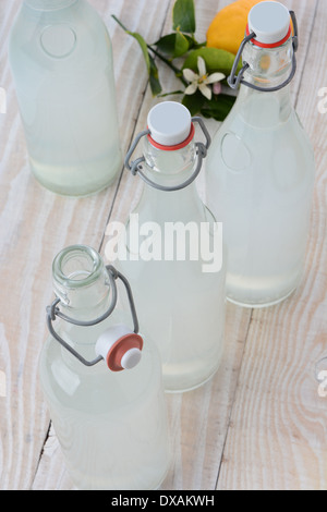In vecchio stile frizzante bottiglie di limonata sparato da un angolo di alta. Formato verticale su un legno rustico stile rustico tavolo. Foto Stock