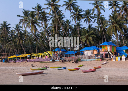 Spiaggia di capanne con alberi di noce di cocco in background e Canoe sulla spiaggia di Palolem Beach in Goa, India Foto Stock