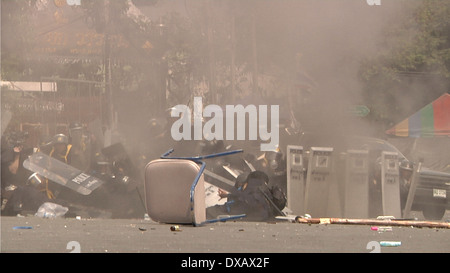Un poliziotto cerca di dare un calcio a una granata lanciato contro di lui dal governo anti-manifestanti a Bangkok, in Thailandia. Foto Stock