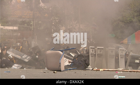 Un poliziotto cerca di dare un calcio a una granata lanciato contro di lui dal governo anti-manifestanti a Bangkok, in Thailandia. Foto Stock