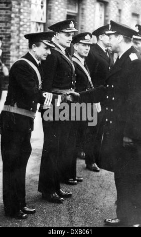 Nella Royal Navy uniforme di King George VI saluta i compagni di ufficiali con una stretta di mano in seguito a una cerimonia di premiazione Foto Stock