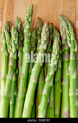 Freschi di punte di asparagi verdi/piccioli contro lo sfondo di legno, REGNO UNITO Foto Stock