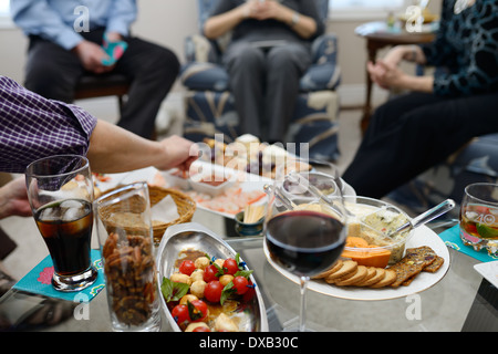 Gruppo di amici gustando stuzzichini e drink nel salotto prima di cena house party Foto Stock